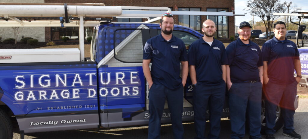Four Signature Garage Doors employees standing in front of a company truck